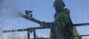 A person spraying pressurized water onto a window